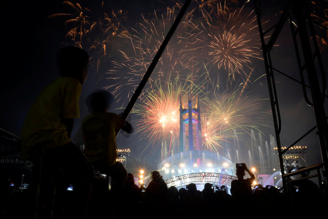 Revellers watch as fireworks explode over the Quezon Memorial Circle during New Year's celebrations in Quezon City, Metro Manila, Philippines January 1, 2017. REUTERS/Ezra Acayan
